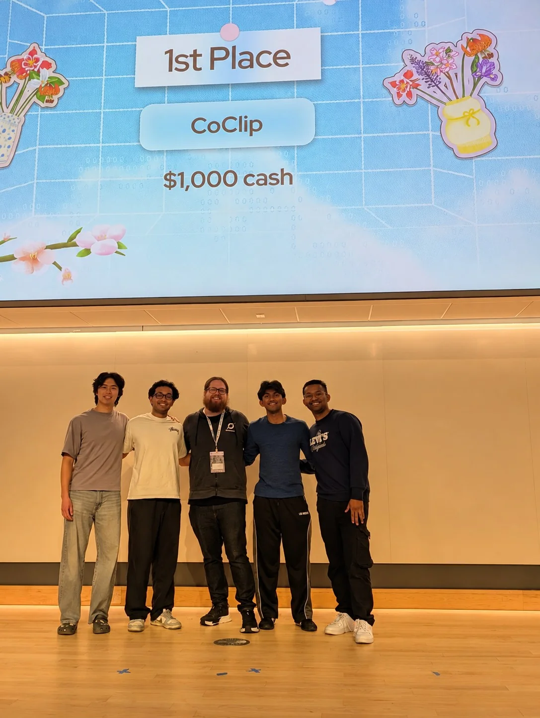 John with the four CoClip team members beneath the screen announcing first place and their $1,000 prize.